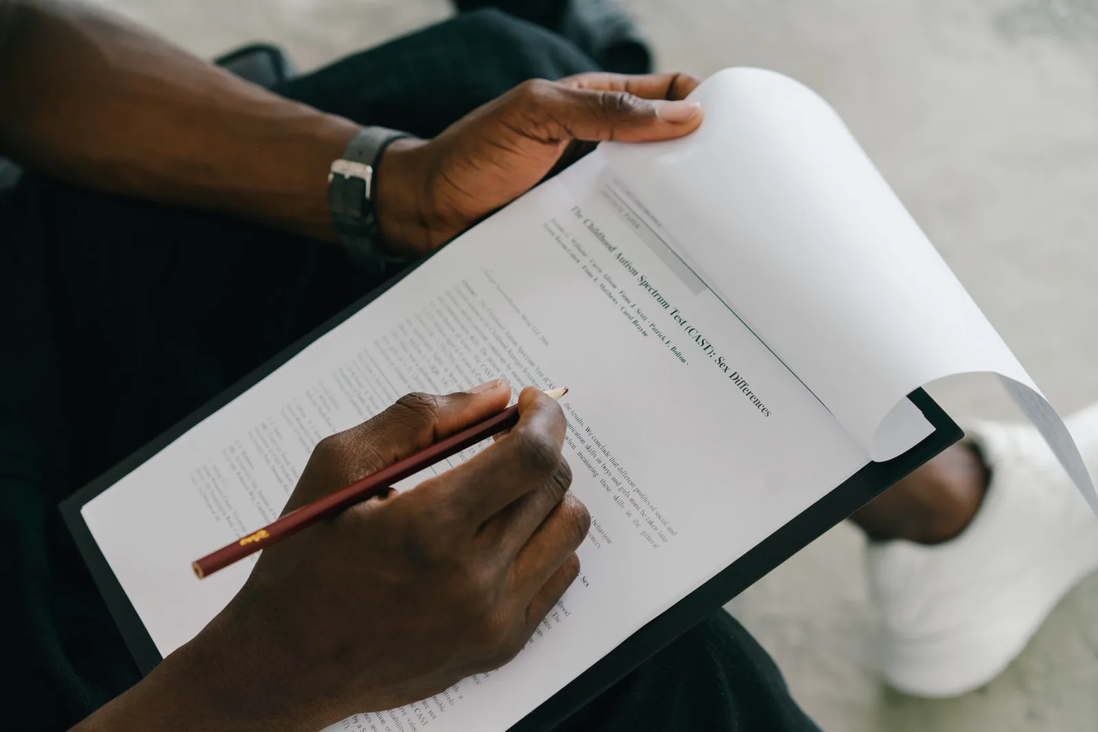 Close-up of a person writing on a psychological assessment form with a pencil.