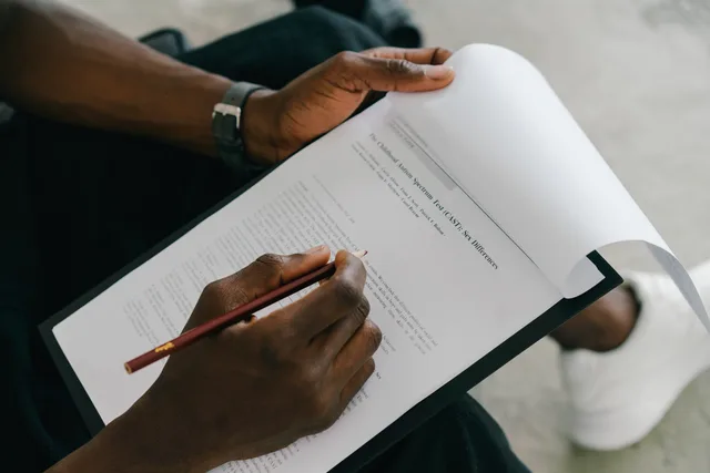 Close-up of a person writing on a psychological assessment form with a pencil. Hvilke fejlkilder bør du kende i spørgeskemaundersøgelser?
